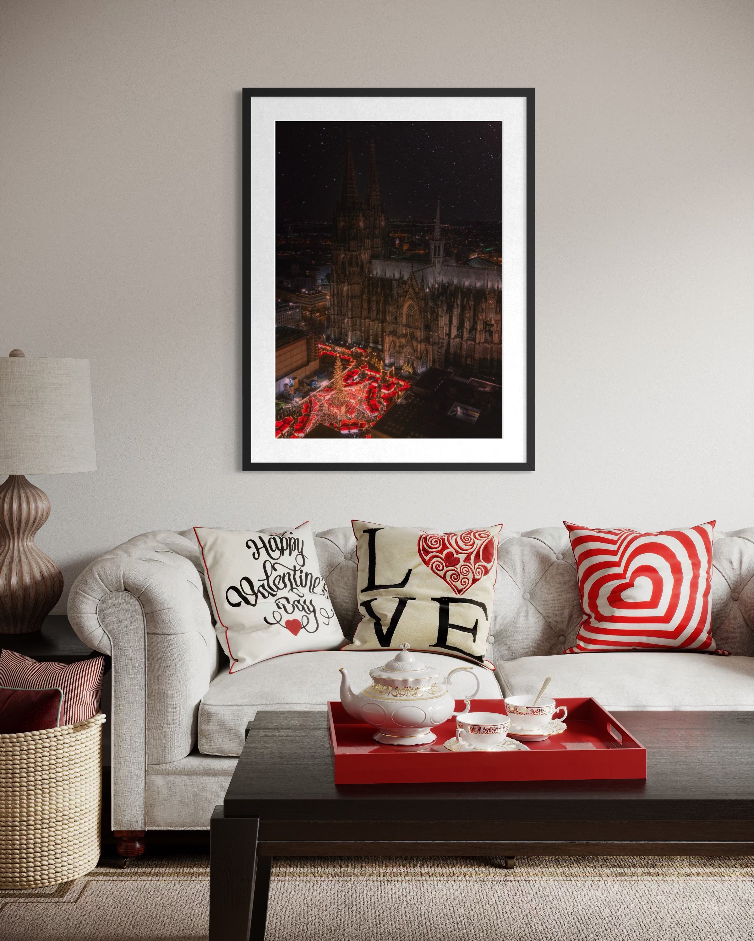 Living room with a framed Cologne Christmas Market artwork above a sofa featuring decorative pillows and a red tray.