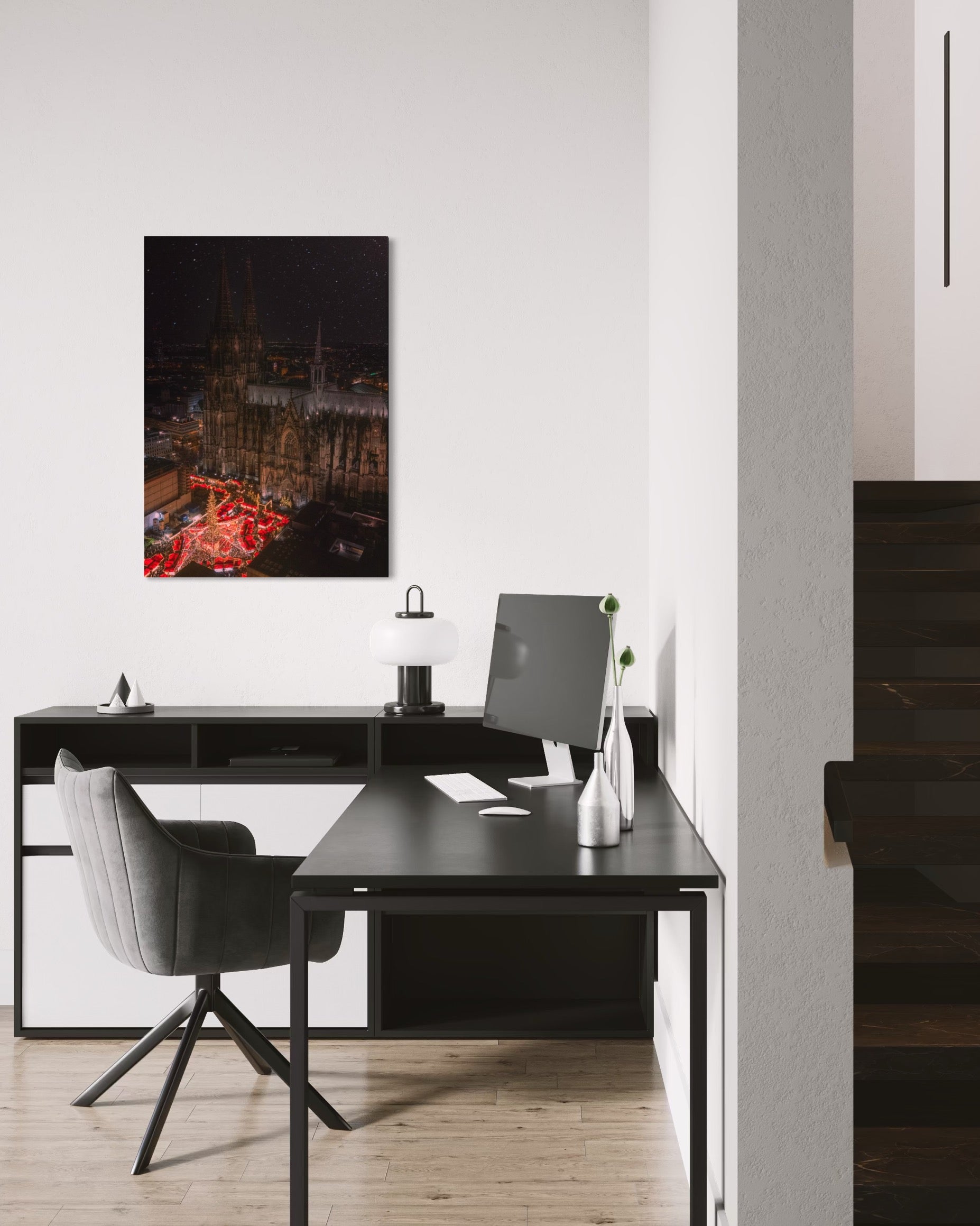 Modern office desk with chair, computer monitor, and Cologne Christmas Market artwork in a minimalistic room.